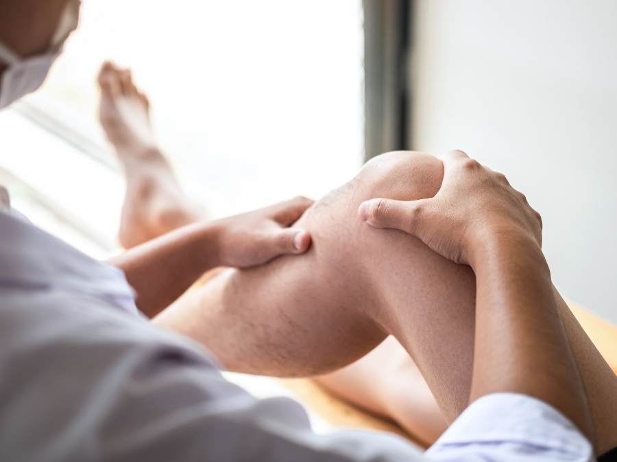 Medico ortopedico durante la valutazione del ginocchio di un paziente con artrosi