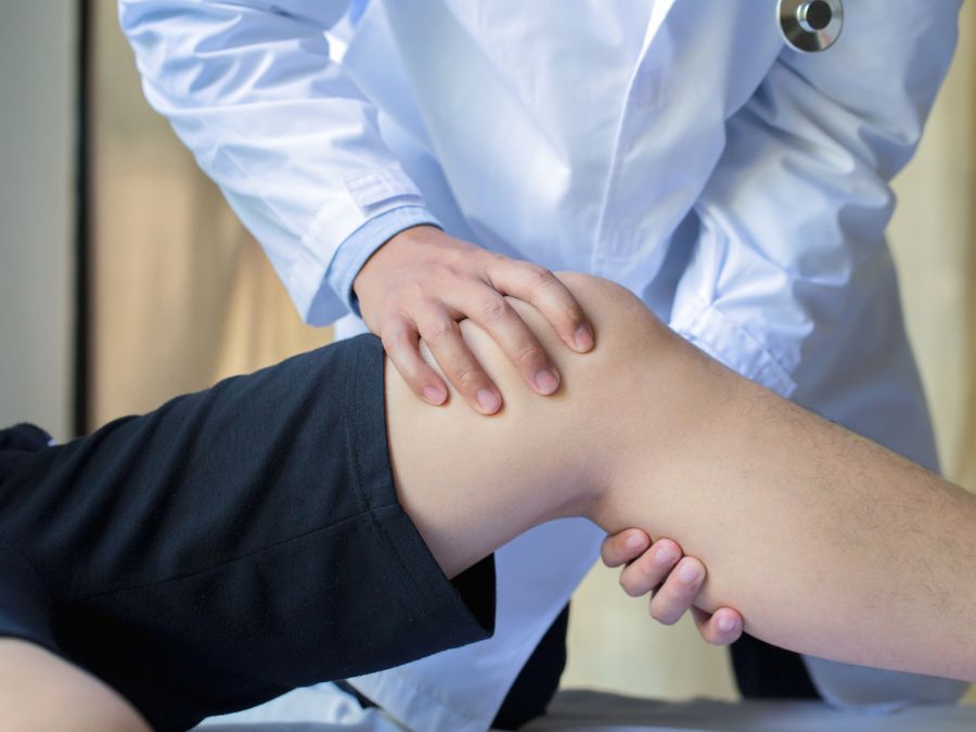 Ortopedico che esamina il ginocchio di un paziente durante una visita medica
