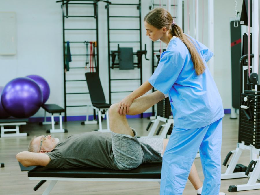 Fisioterapista che assiste un paziente durante la riabilitazione post-protesi al ginocchio